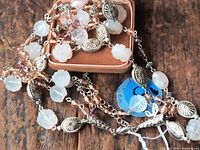 Full view of necklace coiled on box showing carved flower beads, silver-tone spacers, glass beads.