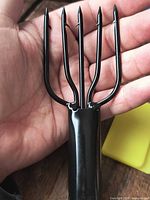 Black four-prong spear head shown in hand for scale