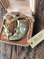 Front view of gold-plated crescent moon brooch with bunny, stars, rhinestones, JJ tag visible in box
