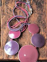 Necklace laid out showing five purple discs and multistrand cord