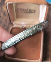 Bangle in jewelry box showing engraved floral pattern