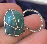 Ring held in fingers showing aventurine stone and wire cage