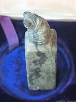 Front view of soapstone seal showing carved beast and marbled stone