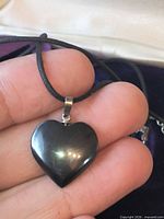 Hand holding hematite heart pendant showing front
