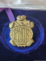 Front view of brass PWOR cap badge