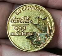 Front of gold-tone Coca-Cola Olympic coin showing Go Canada design
