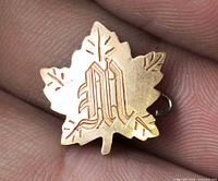 Front view of maple leaf pin showing monogram M