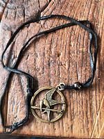 Full view of necklace laid out on wood surface showing pendant and cord