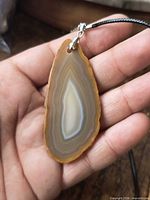Front view of agate slice pendant showing banding and bail on cord