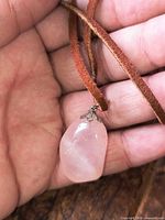 close-up of rose quartz pendant in hand showing bail and cord