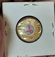 Reverse of 25-cent coin with pink ribbon motif inside 2x2 flip