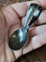 Spoon in hand showing curled handle and bowl