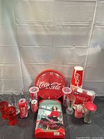 Group shot of all Coca-Cola items including clock, Barbie, glasses and party supplies