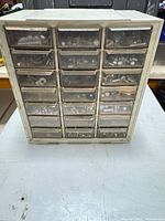 Front view of cabinet showing 24 drawers filled with metal hardware