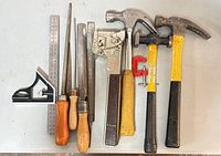Group shot of all tools: combination square, steel rule, four files, staple gun, C-clamp, three hammers