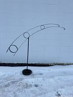 Full view of freestanding metal plant hanger against wall