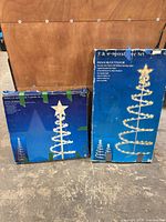 Two Bright Tidings spiral Christmas tree set boxes showing product graphics and size information