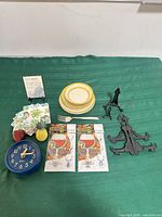Lot overview showing plates, coasters, wine charms, clock, stands, fork, plaque