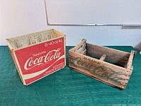 Wooden slat Coca-Cola crate and red cardboard Coca-Cola carrier side-by-side