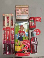 Group view of Barbie doll, lip balm blister packs, can and bottle tins, pharmacy tin