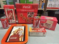 All boxed Coca-Cola items displayed: neon clock, rotating lamp, crate radio, Stepvan bank, metal tray, two cans