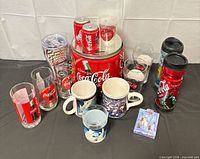 Group view of all Coca-Cola drinkware, tin bank, shakers, playing cards