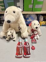 Group shot of all items: four plush bears, two bottle tins, lighter keychain, boxed lanyard