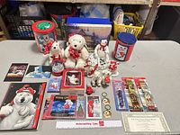 Overview of entire lot on table showing plush bear, tins, figurines, snow globe, stationery and other collectibles