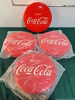 Top view of four Coca-Cola seat tops, three sealed, one unwrapped