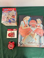 Group view of all four Coca-Cola items: boxed polar bear clock, keepsake tin, wall sign, alarm clock