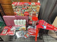 Group shot of all Coca-Cola collectibles including Scrabble, puzzle, chips, tumbler, cards and flags