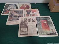 Six Coca-Cola magazine ads laid out on table