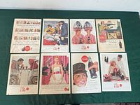 All eight Coca-Cola ads laid out on surface