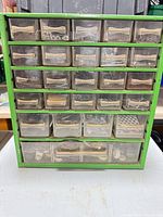 Front view of green metal organizer cabinet showing drawers and contents