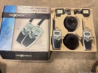 Boxed set showing two radios, chargers and adapters in molded tray