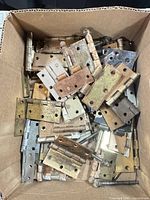 box containing numerous mixed metal butt hinges