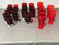 Group of red Coca-Cola glasses and ruby stemmed goblets displayed on table