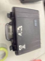 Closed black hard case showing exterior, handle, stickers, overall wear