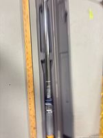 Torque wrench inside open molded case beside ruler showing overall length