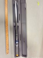 Torque wrench inside open plastic case next to ruler