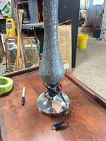 Full view of lamp base showing gray crackle glass body, metal base, power cord