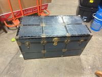 Front view of trunk showing black exterior and brass hardware