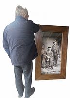 Person standing beside large framed photo to show scale