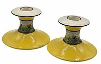 Front view of both yellow ceramic candlesticks showing overall form and hunting scene band