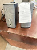 Front view of both Bose speakers showing grilles, controls and overall wear