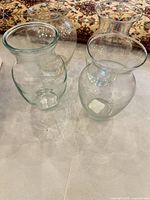 Four clear glass bulbous vases with flared rims grouped together