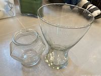 Goblet-style vase and hexagonal jar side by side on floor