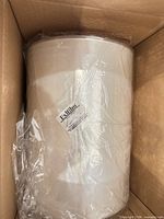 Open carton showing clear shrink film roll with internal core and protective plastic