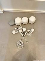 Three white Nest WiFi cylinders, one gray Home Mini, four power adapters, Ethernet cable arranged on floor