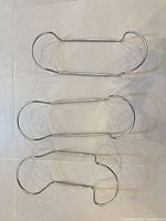Three chrome metal hangers displayed flat
